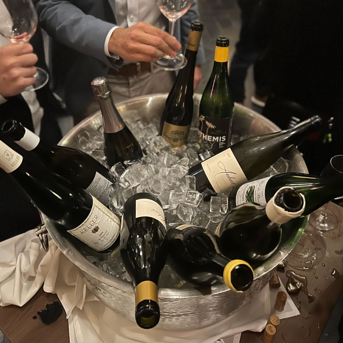 Bottles of Fine and Rare wine in an Ice bucket. Formally dressed people gathered around
